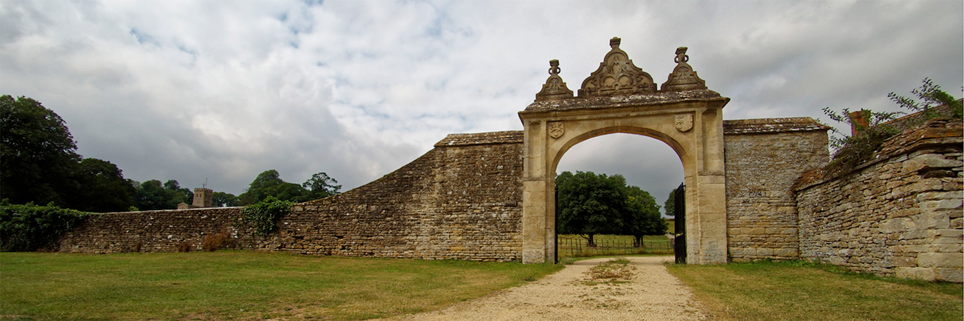 Dry stone wall, rising at the right into an archway.