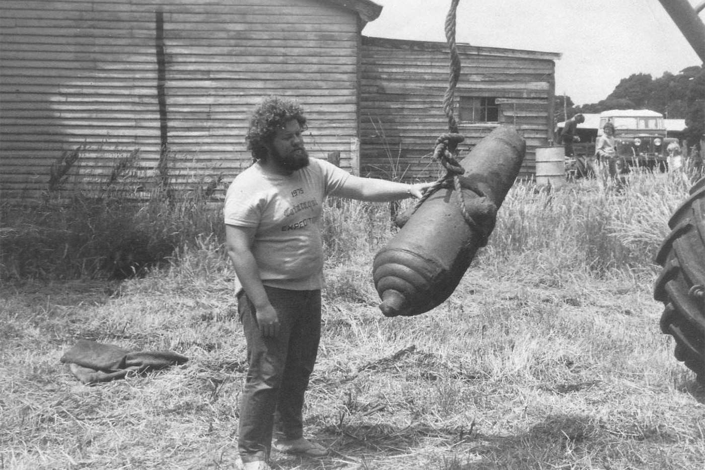 Man standing with the remains of a cannon suspended by a rope from a crane.