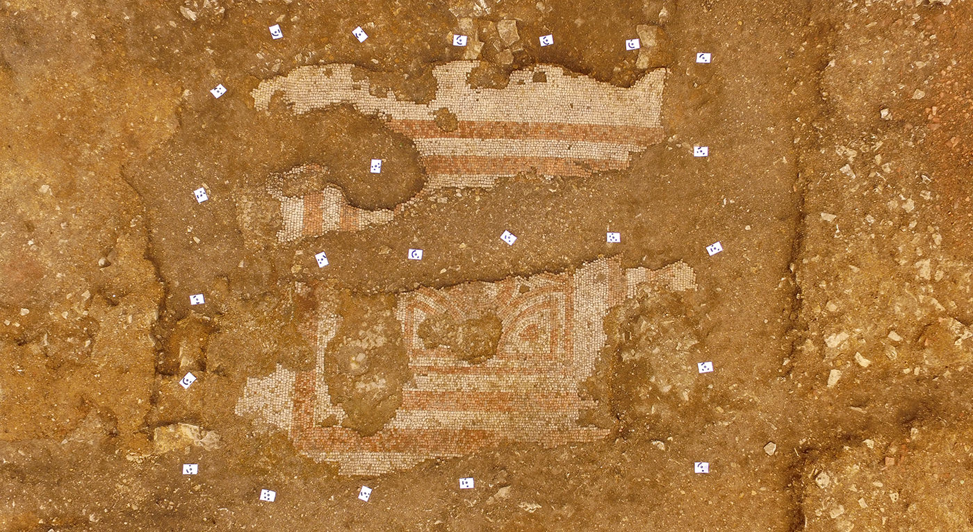 Aerial view of the partially unearthed mosaic floor showing its reddish pattern.