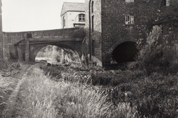 Brick building and adjoining bridge over a canal. The towpath is in the foreground.