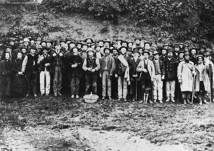 Fifty or more men and women, in varying attire, assembled in a close group for a photograph.